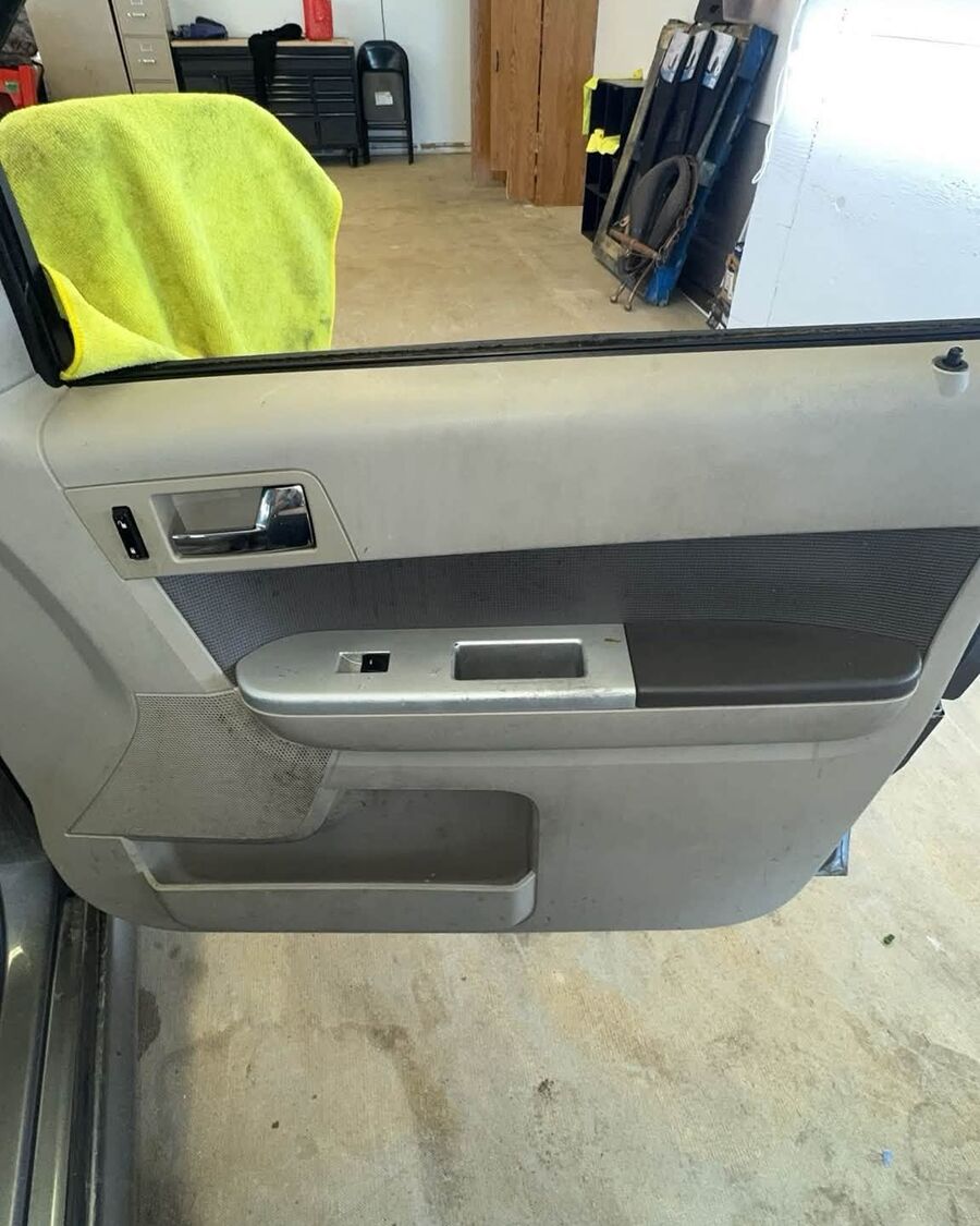 Driver door panel before, dusty with scuffs on the lower trim